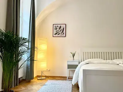 a white bedroom with a bed and a plant at Prague apartment 3 minutes from historical town in Prague