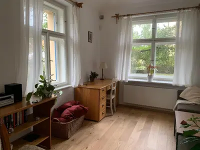 a living room with two windows and a table and a desk at Art nouveau villa with garden close to center in Prague