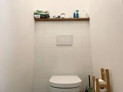 a bathroom with a toilet and a shelf on the wall at Charming 1BDR nest with balcony in Prague