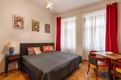 a bedroom with a bed with red curtains and a table at 2 bedroom apartment in New Town close to river in Prague