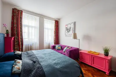a bedroom with a purple bed and a couch at Cozy Central apartment by Charles Square in Prague