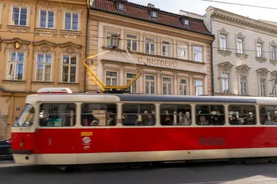 a red and white tram in front of a building at Cozy Central apartment by Charles Square in Prague