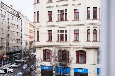 a tall white building with red windows on a city street at Prime Location Modern flat in Prague centre in Prague