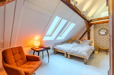 a attic bedroom with a bed and a chair at Jevany Four Bedroom Luxury Villa by the Lake with Infrasauna and Grill in Jevany