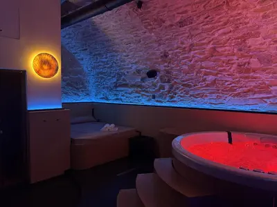 a bathroom with a red bath tub and a stone wall at SPA SPA Petrská in Prague