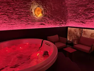 a red bath tub in a room with a rock wall at SPA SPA Petrská in Prague