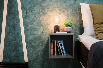 a book shelf with a lamp on it next to a bed at Twin Residence Retro-Cinematic Apartment in City Centre in Prague