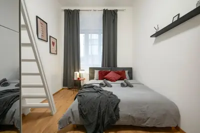 a bedroom with a bed and a ladder next to a window at Downtown Comfort in a Spacious Apartment in Prague