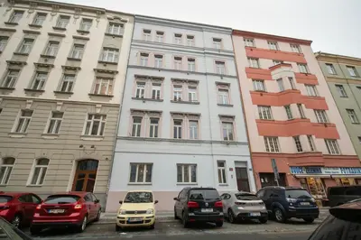 a large white building with cars parked in a parking lot at Downtown Comfort in a Spacious Apartment in Prague