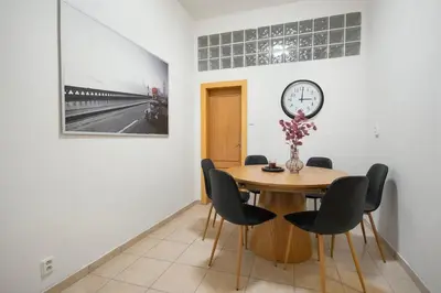 a dining room with a table and a clock on a wall at Downtown Comfort in a Spacious Apartment in Prague