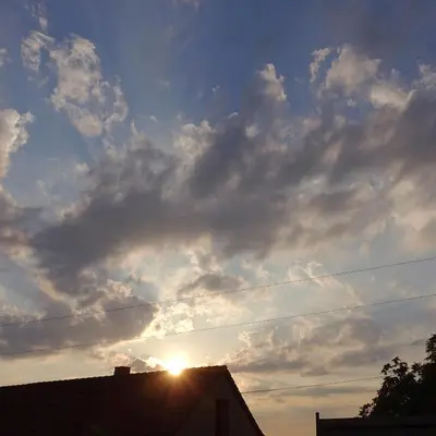 a cloudy sky with the sun behind a building at Chalupa Kdovíkde in Budyně nad Ohří