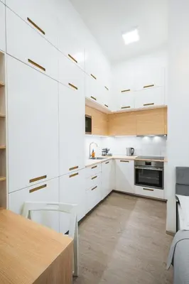a kitchen with white cabinets and a wooden table at Central Studio Apartment with Parking - Near Main Train Station & Wenceslas Square in Prague