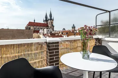 a table and chairs on a balcony with a vase of flowers at Central Apartment with breathtaking view in Prague