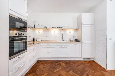 a white kitchen with wooden floors and white cabinets at Central Apartment with breathtaking view in Prague