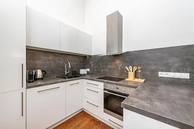a kitchen with white cabinets and stainless steel appliances at Stunning 2 bed in prime central location in Prague