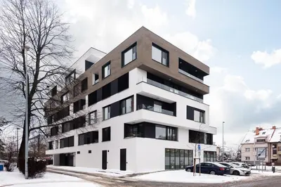 a white building with black windows in the snow at Prague Modern Apartment in Prague