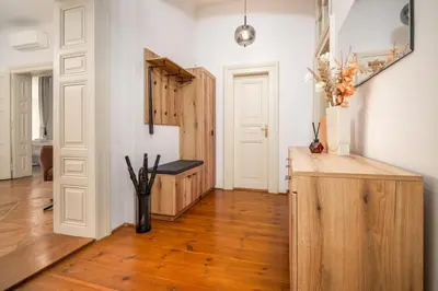 a room with a vase of flowers on a wooden floor at Trendy Apt Centrally Located with PS5, AC, balcony in Prague
