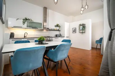 a kitchen with a table and blue chairs at Trendy Apt Centrally Located with PS5, AC, balcony in Prague