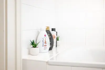 a bathroom sink with a bottle of shampoo and a plant at Trendy Apt Centrally Located with PS5, AC, balcony in Prague
