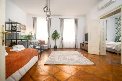 a bedroom with a bed and a room with two windows at Trendy Apt Centrally Located with PS5, AC, balcony in Prague