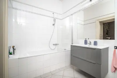 a white bathroom with a tub and a sink at Trendy Apt Centrally Located with PS5, AC, balcony in Prague