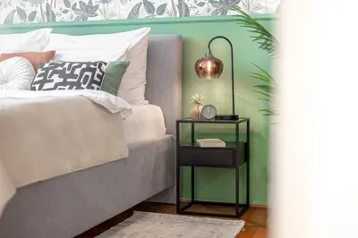 a bedroom with a bed and a side table with a lamp at Trendy Apt Centrally Located with PS5, AC, balcony in Prague