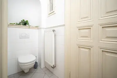 a white bathroom with a toilet and a door at Trendy Apt Centrally Located with PS5, AC, balcony in Prague
