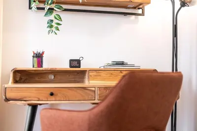 a wooden desk with a chair next to a wall at Trendy Apt Centrally Located with PS5, AC, balcony in Prague