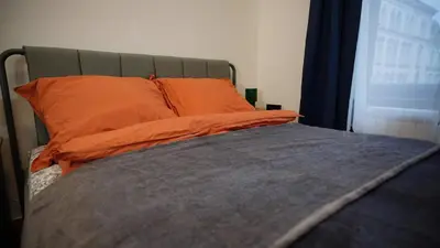 a bed with an orange pillow and a window at Spacious 2 Bedroom Apartment in Prague 2 in Prague