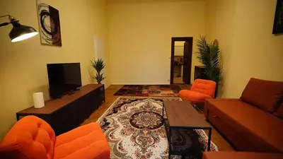 a living room with an orange couch and a tv at Spacious 2 Bedroom Apartment in Prague 2 in Prague