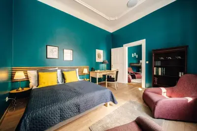 a bedroom with blue walls and a bed and a chair at Spacious 3BR Apartment with Billiards & Cinema in Prague