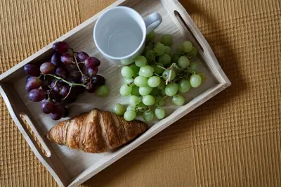 a tray with grapes a croissant and a cup at Sudomerská 5, Zizkov, Czech Republic in Prague