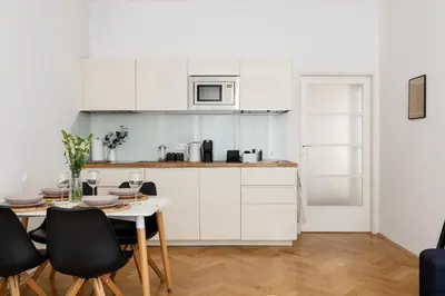 a kitchen with white cabinets and a table and chairs at Sudomerská 5, Zizkov, Czech Republic in Prague