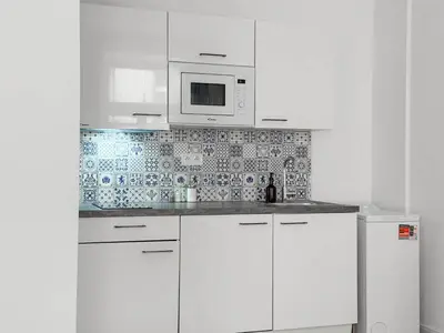 a white kitchen with white cabinets and a microwave at REAL Living by REFA - New Town 210 in Prague