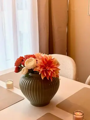 a green vase filled with flowers on a table at My Sweet Home - Makedonská - Prague in Prague