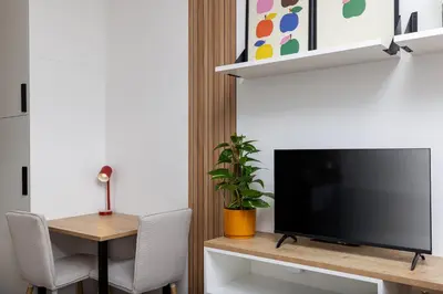 a living room with a television and a table with chairs at Modern Apartment Near Anděl & Metro in Prague