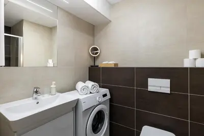 a bathroom with a washing machine and a sink at Modern Apartment Near Anděl & Metro in Prague