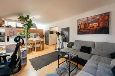 a living room with a gray couch and a kitchen at QUIET apartment with FREE parking & balcony in Prague