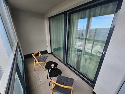 an apartment balcony with two chairs and a large window at Centre NEW modern apartment & parking near O2 arena in Prague