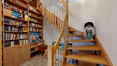 a wooden staircase in a room with bookshelves at La Casa Colorata apartment in the hearth of Prague in Prague