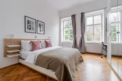 a white bedroom with a bed and two windows at Blueground Malá Strana view nr Prague Castle PRG-94 in Prague