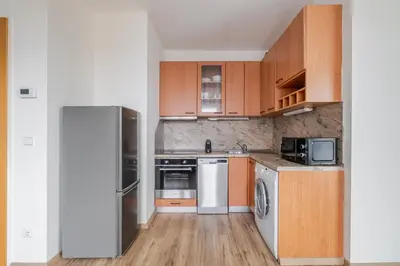 a kitchen with wooden cabinets and a refrigerator at Blueground Vinohrady pool nr Vyšehrad PRG-88 in Prague