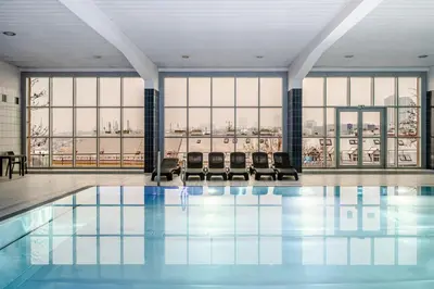 a pool with chairs in a large room with windows at Blueground Vinohrady pool nr Vyšehrad PRG-88 in Prague