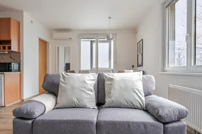 a living room with a gray couch with pillows at Blueground Vinohrady pool nr Vyšehrad PRG-88 in Prague