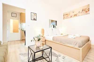a white bedroom with a large bed and a table at Casa Center Apartments in Prague