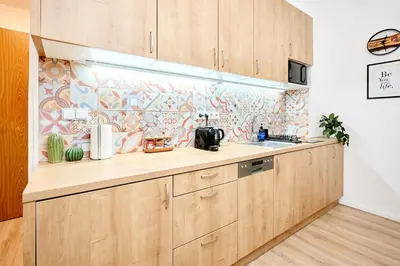 a kitchen with wooden cabinets and a tile wall at Casa Center Apartments in Prague