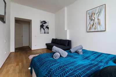 a bedroom with a blue bed and a black couch at Golden Aurora Prague in Prague