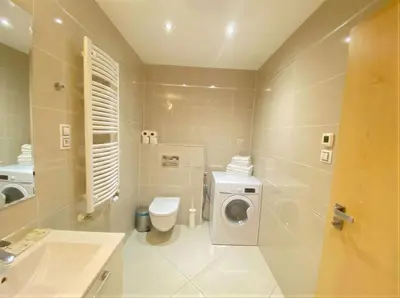 a bathroom with a toilet and a washing machine at Fortuna Garden V in Prague