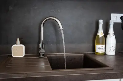 a kitchen sink with a faucet and a bottle of wine at Bohemian Luxe Central in Prague
