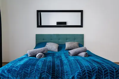 a bed with a blue comforter and a mirror at Bohemian Luxe Central in Prague
